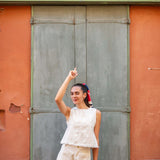 Woman in a white outfit posing in front of a green and orange building with 'Cassis' written on it.