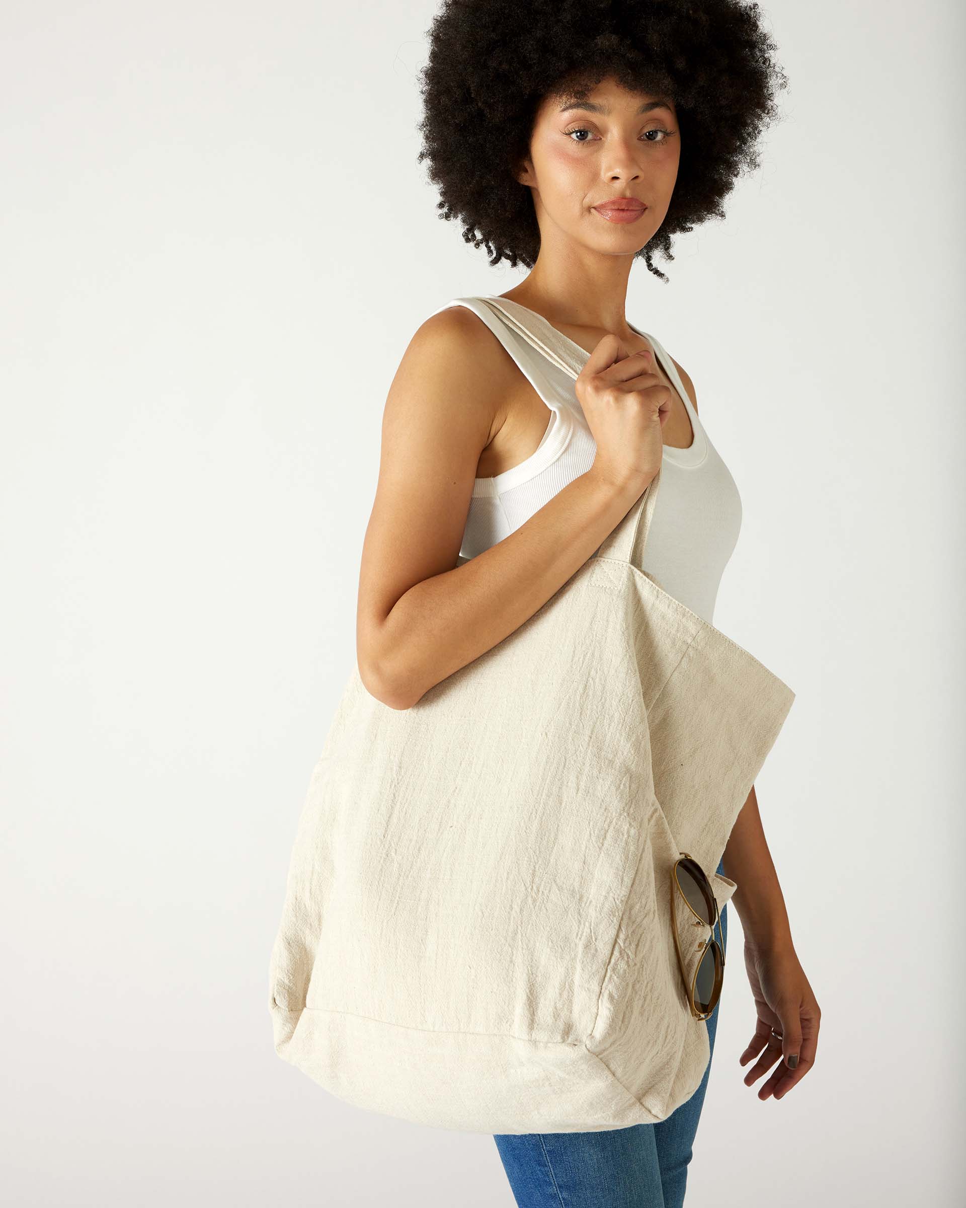 profile of woman with mersea oversized canvas tote in neutral flax over shoulder