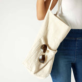 closeup of tote on woman with mersea oversized canvas tote in neutral flax over shoulder