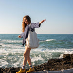 woman with mersea oversized canvas tote in neutral flax over shoulder balancing on log near water