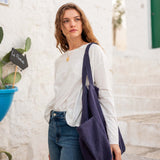 woman with mersea oversized canvas tote in navy blue standing on steps in front of white buildings