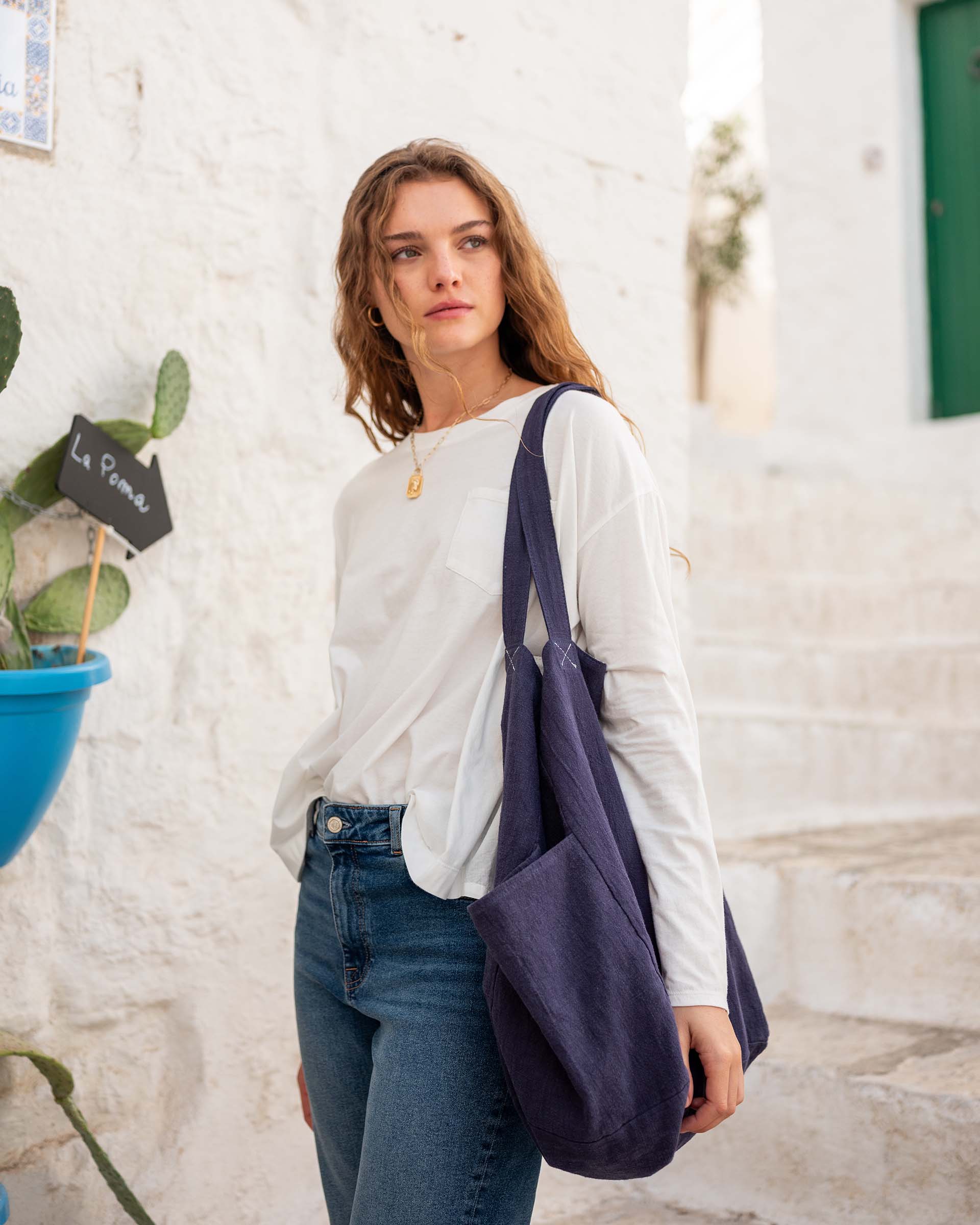 woman with mersea oversized canvas tote in navy blue standing on steps in front of white buildings