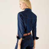 Back view of women's travel-friendly dark blue denim button-up shirt with flared cuffs and matching jeans.