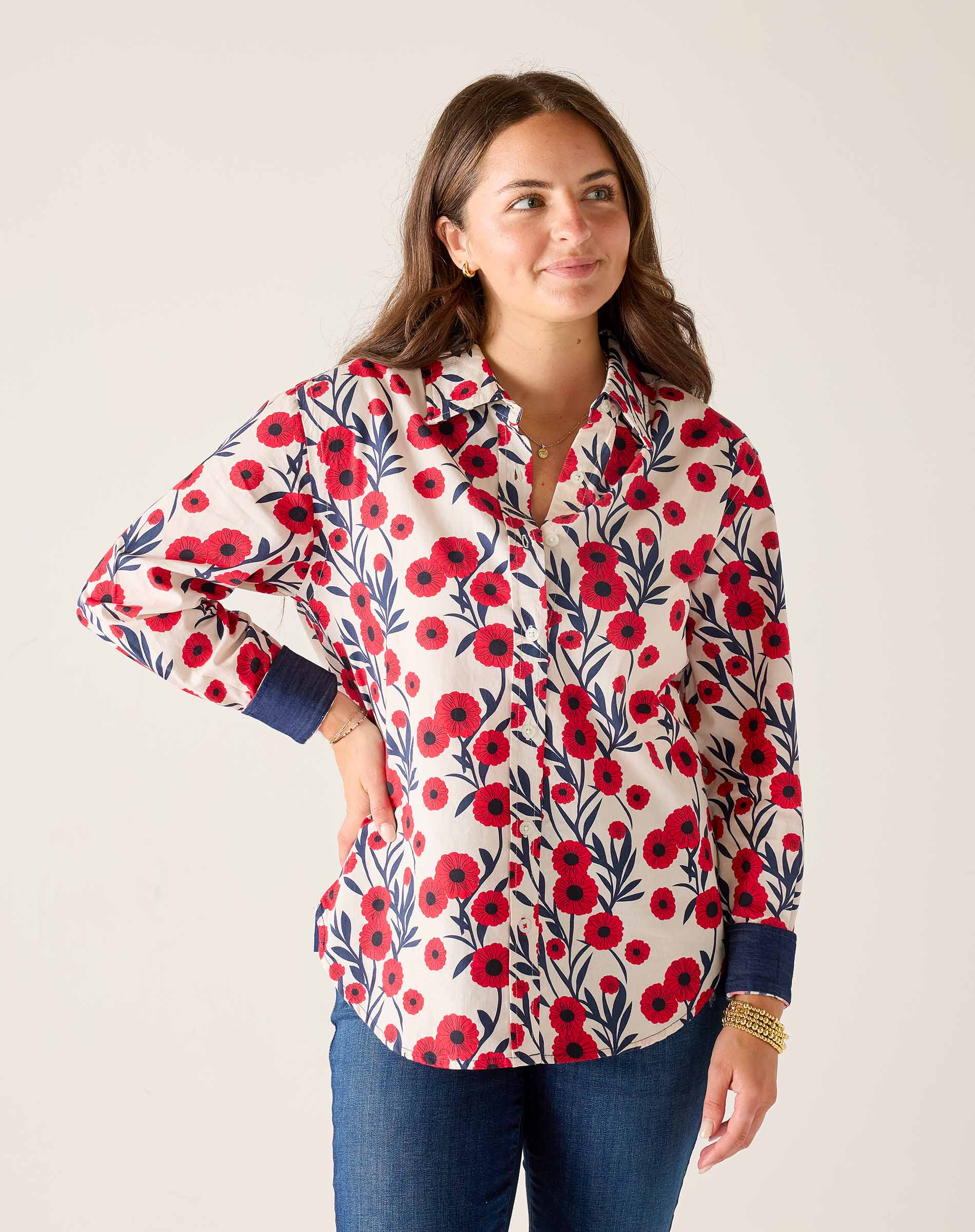Woman wearing a floral patterned shirt with red flowers on a white background