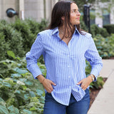 Woman wearing a blue striped shirt and jeans standing outdoors.