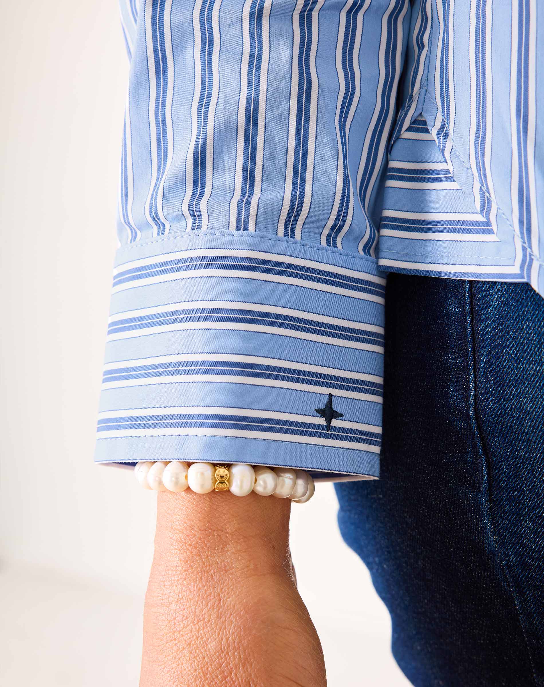 Blue and white striped button-up shirt with a contrast cuff detail.