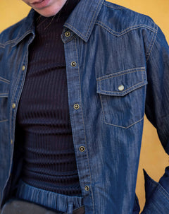 Women's travel-friendly blue denim button-up shirt with chest pockets and button details.