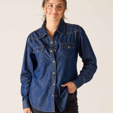 Woman wearing a blue denim shirt against a plain background