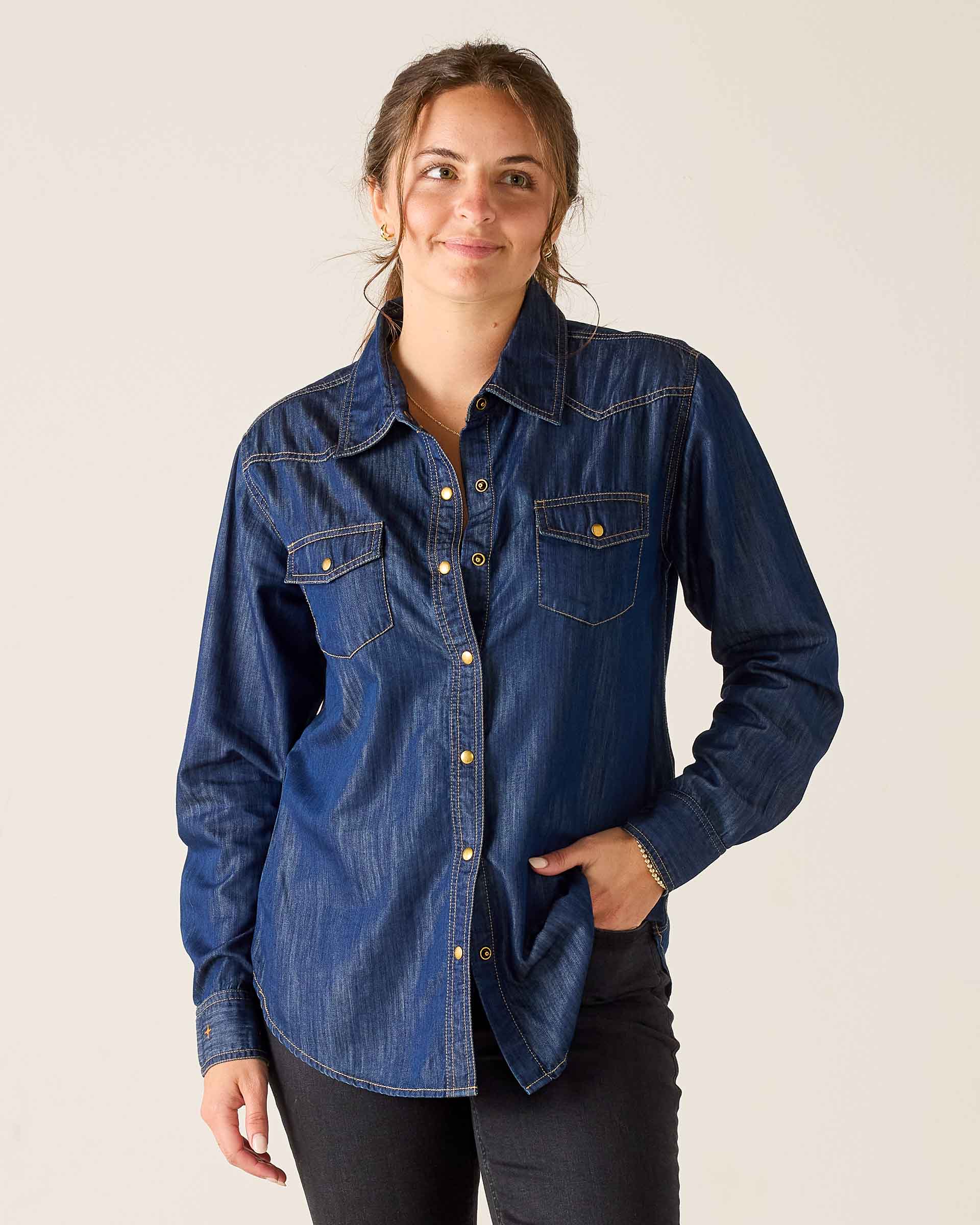 Woman wearing a blue denim shirt against a plain background
