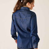 Woman wearing a blue denim shirt against a plain background