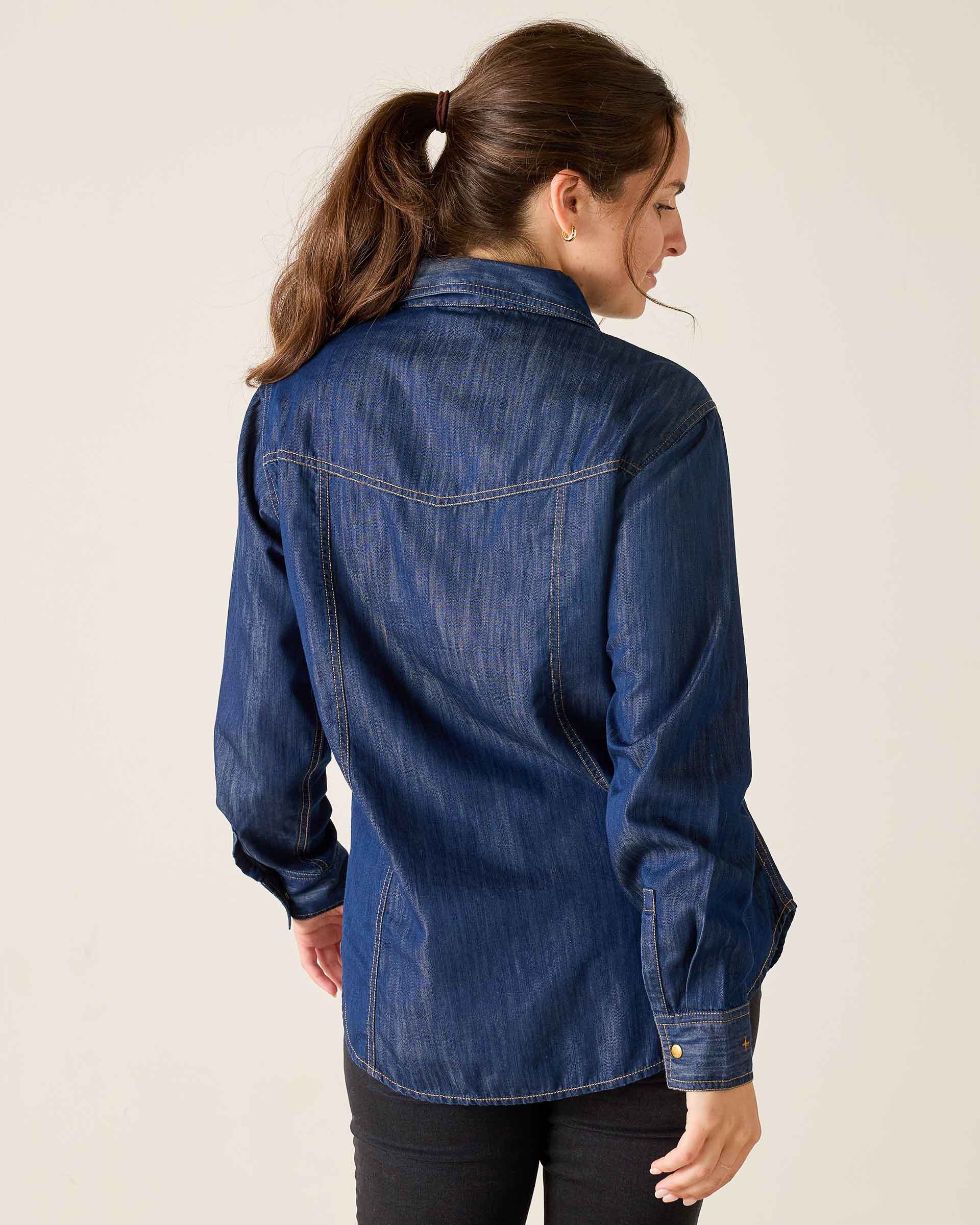 Woman wearing a blue denim shirt against a plain background