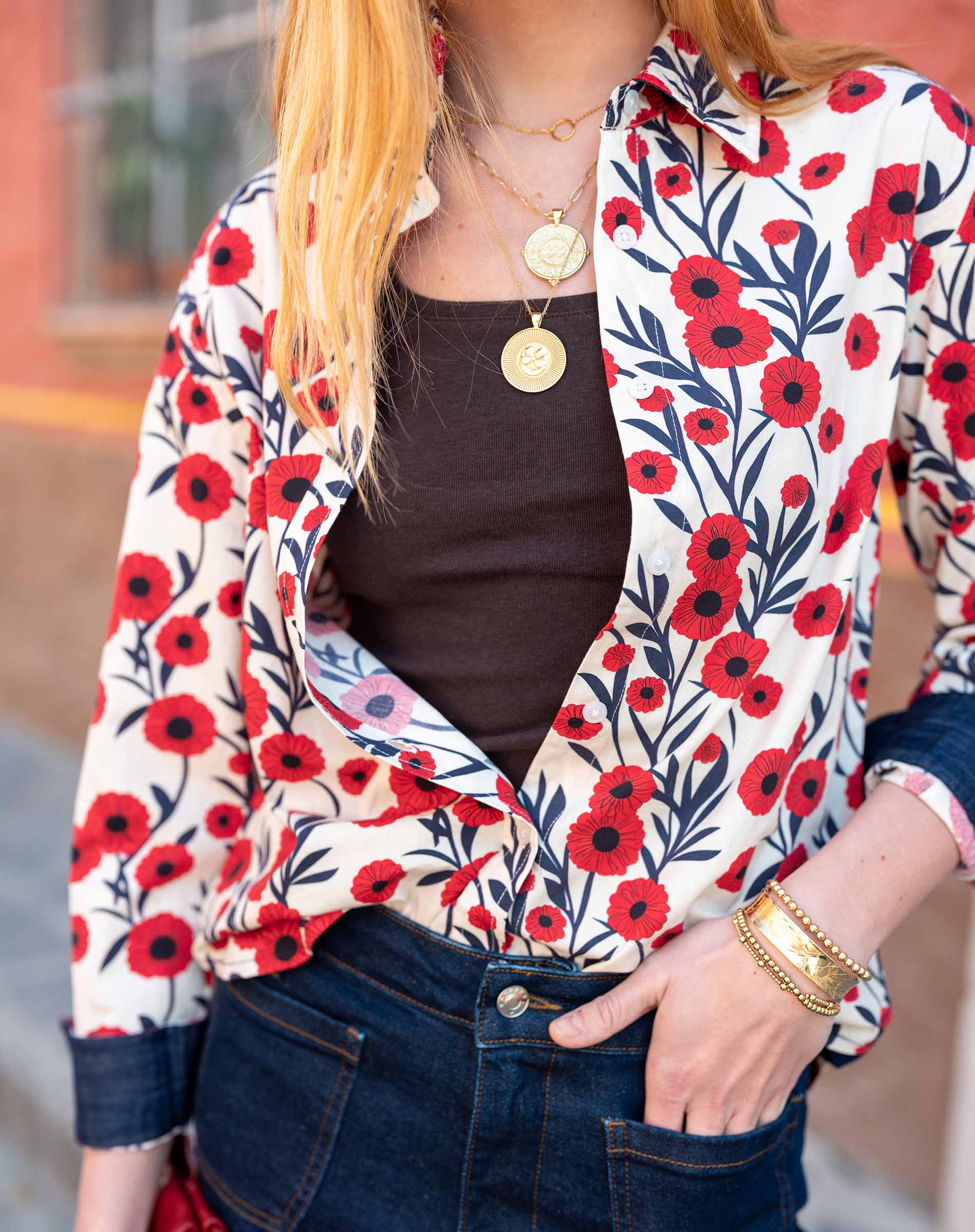 Person wearing a floral jacket with red flowers and a blurred background