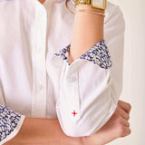 Close-up of a person wearing a white shirt with floral cuffs and a gold watch.