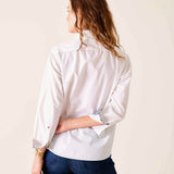 Person wearing a white shirt with rolled-up sleeves on a plain background