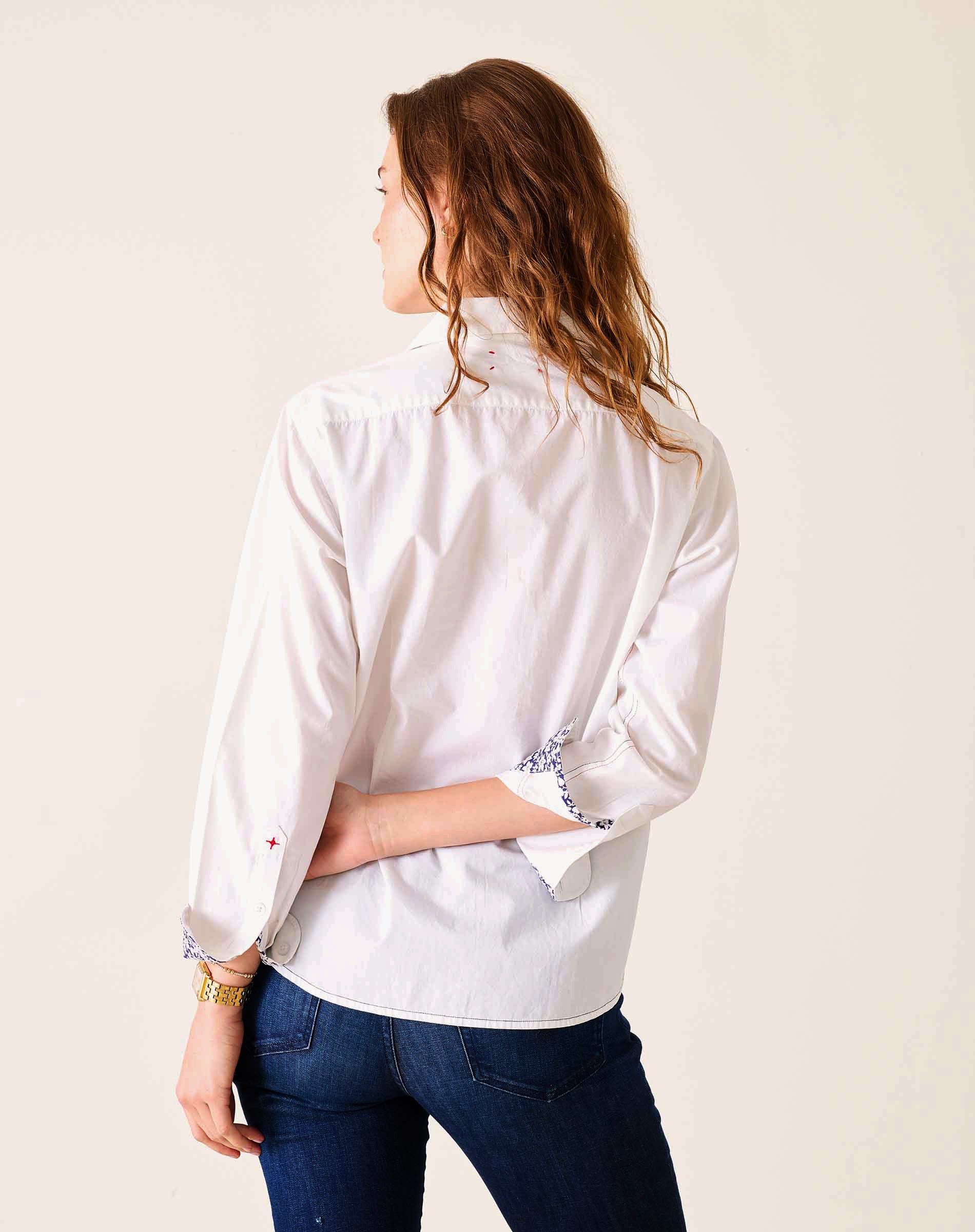 Person wearing a white shirt with rolled-up sleeves on a plain background