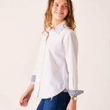 Woman wearing a white shirt with patterned cuffs on a plain background