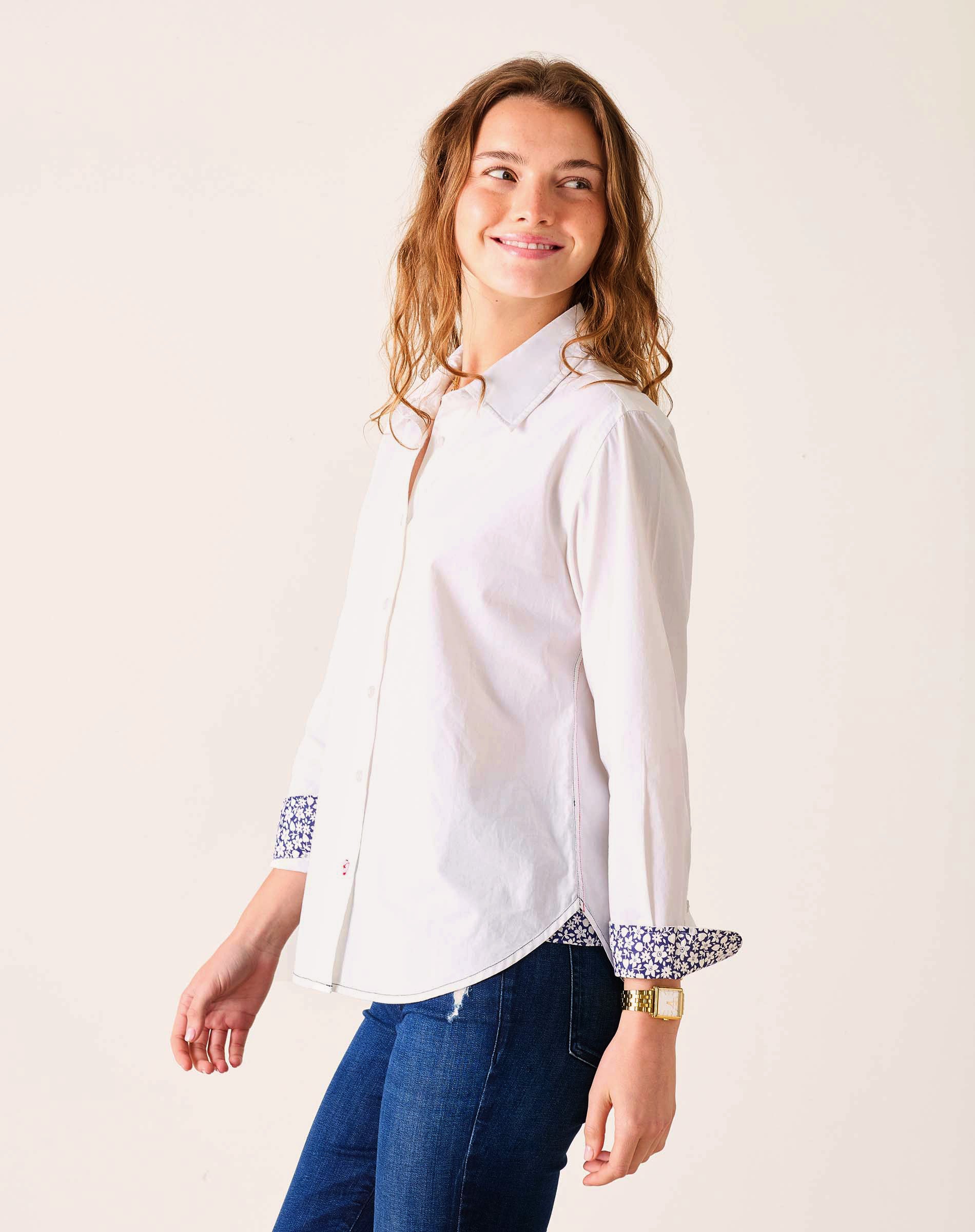 Woman wearing a white shirt with patterned cuffs on a plain background