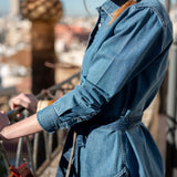 Chambray blue button-up shirt with a tie waist and long sleeves.