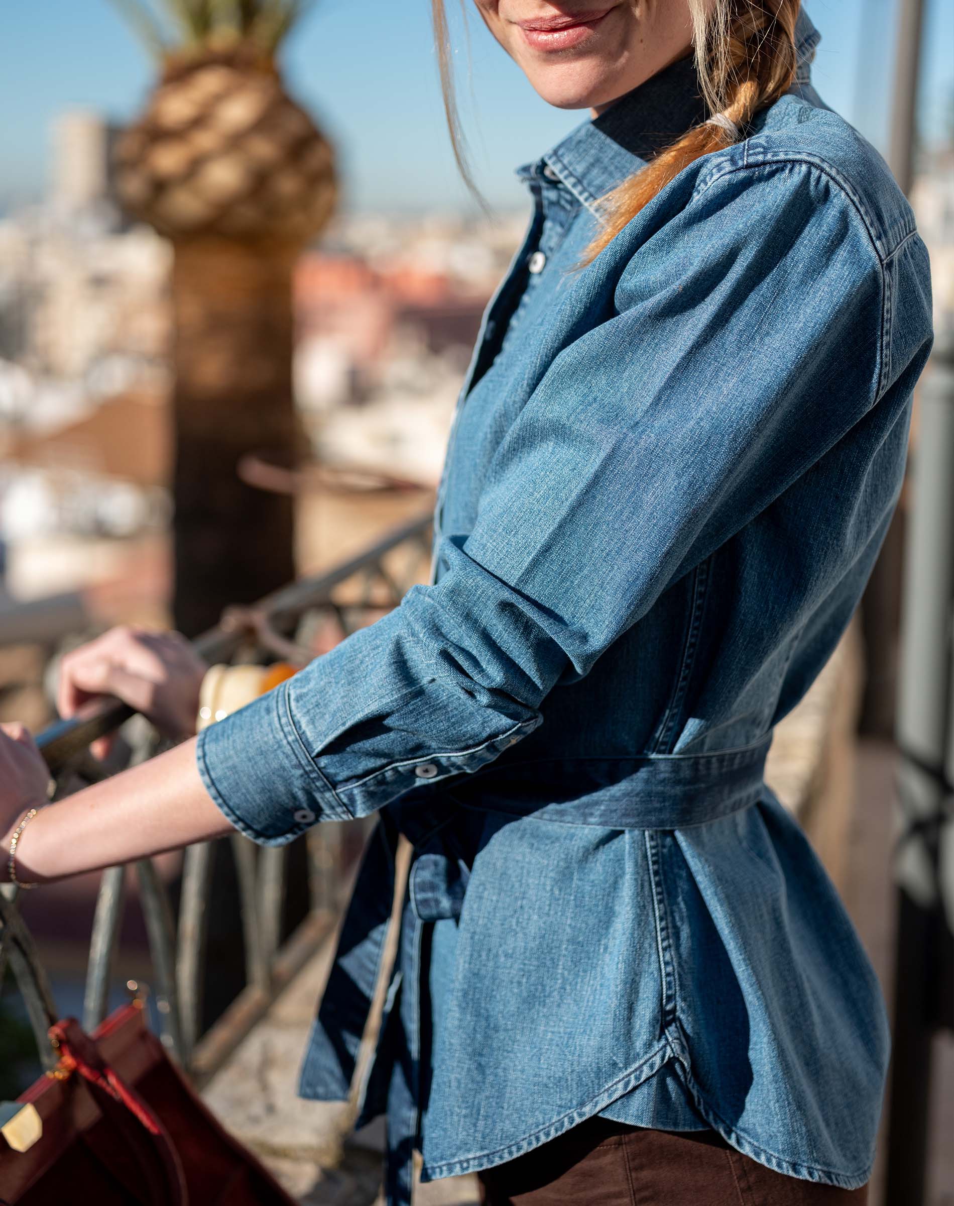 Chambray blue button-up shirt with a tie waist and long sleeves.
