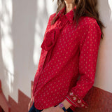 Crimson red button-up shirt with small geometric patterns and tie details on the front.