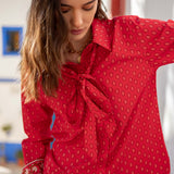 Crimson button-up shirt featuring a small repeating pattern and a large front bow detail.