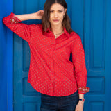 Crimson red button-up shirt with a small repeating dot pattern and embroidered details on the cuffs.