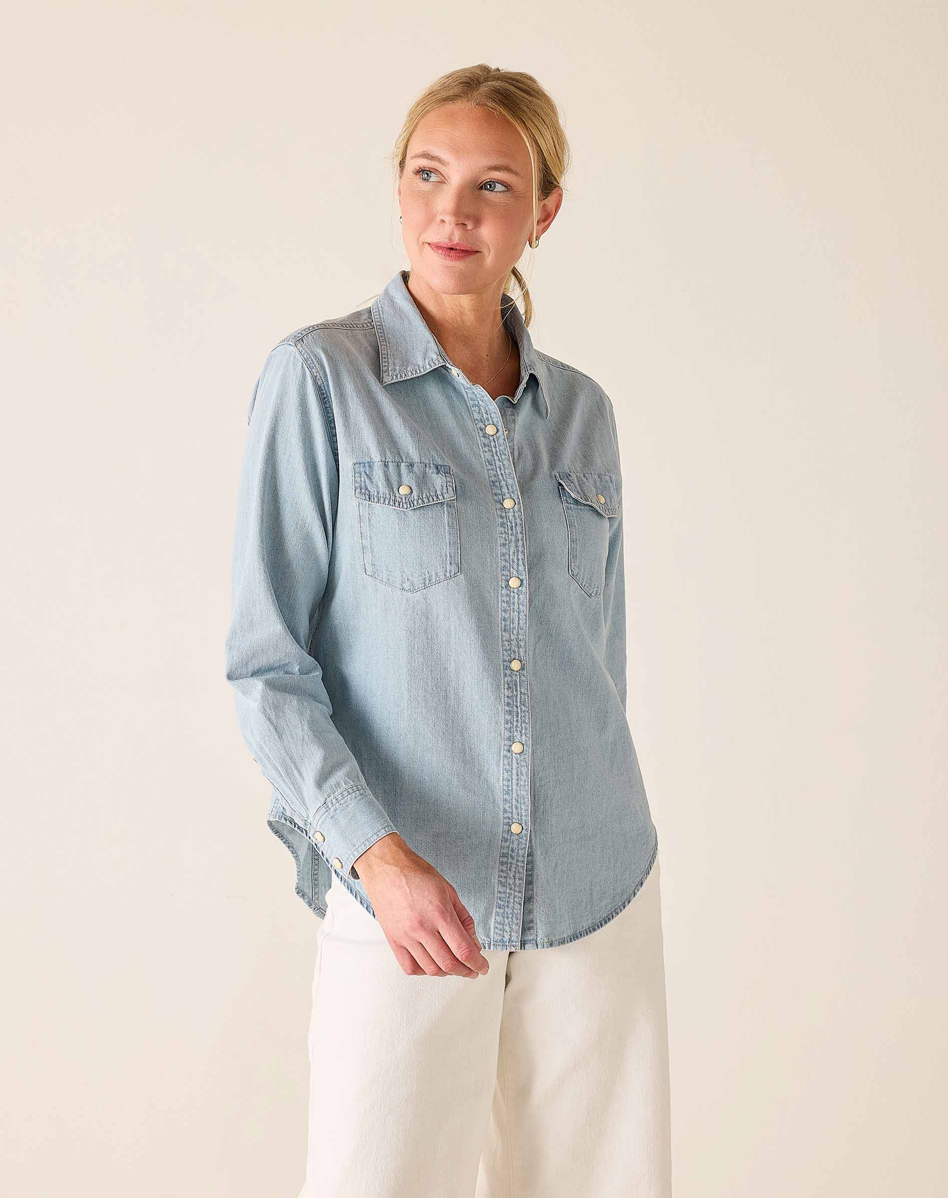Woman wearing a light blue denim shirt against a plain background