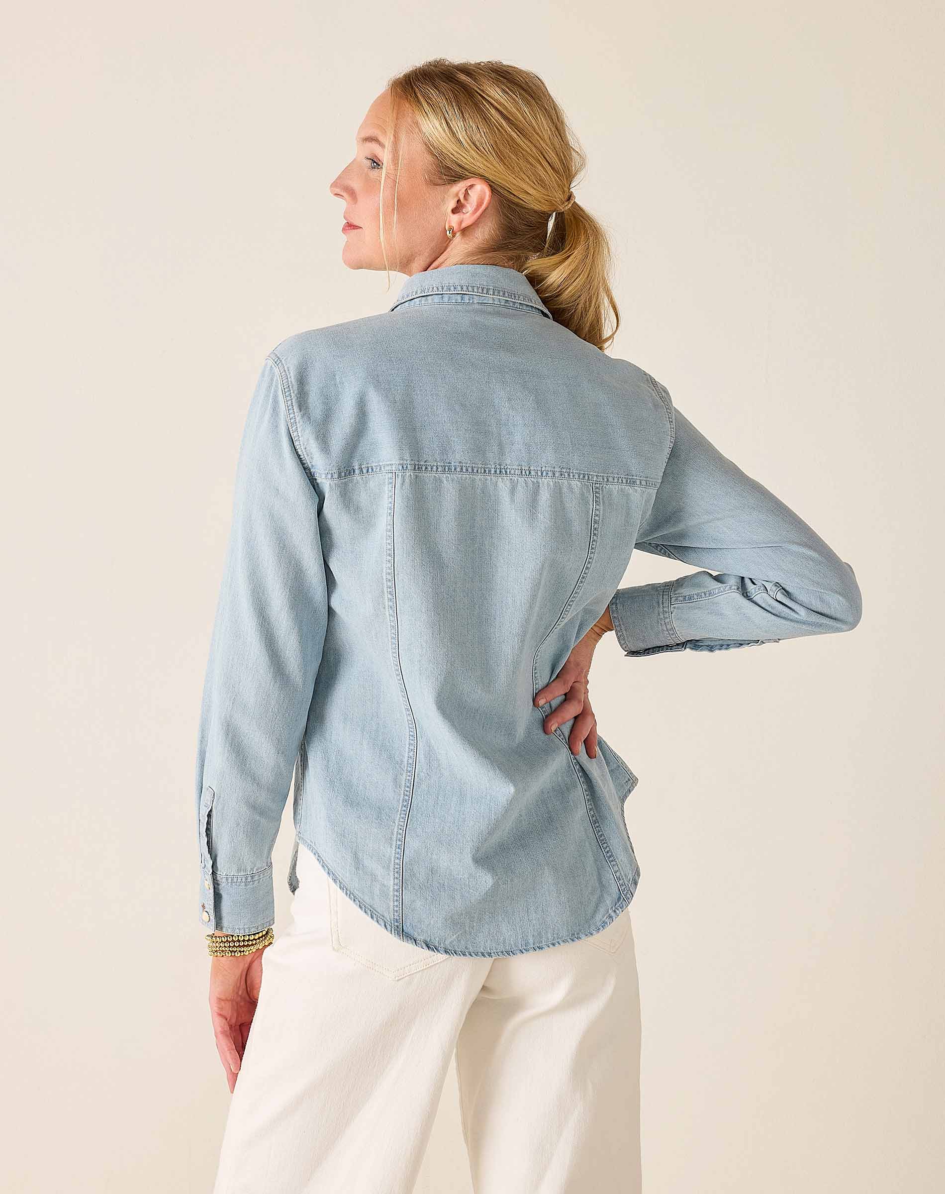 Woman wearing a light blue denim shirt against a beige background