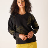 Women's travel-friendly black knit sweatshirt with gold-toned floral embroidery and a V-neckline.