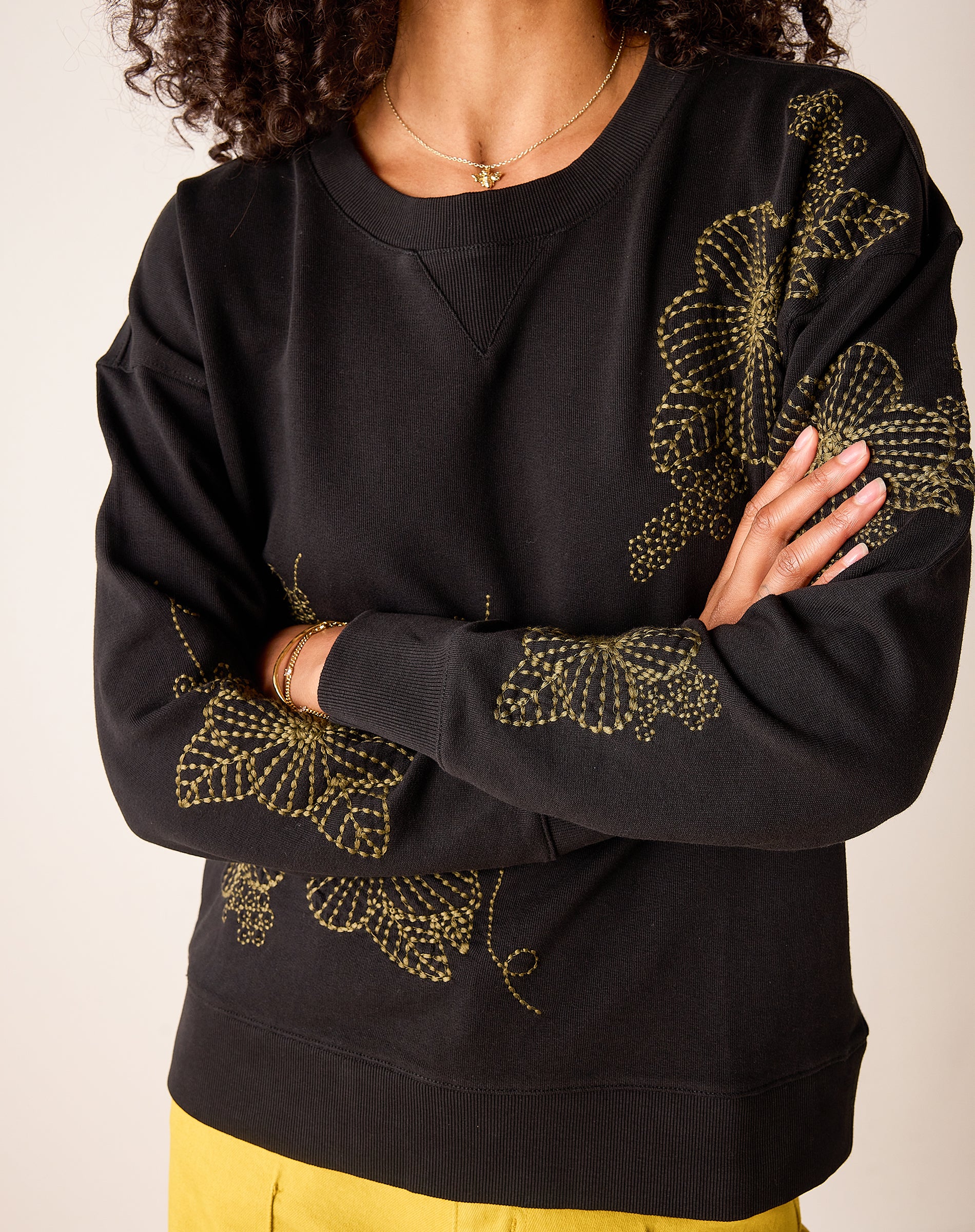 Military green relaxed-fit knit sweatshirt with yellow embroidered daisy details.