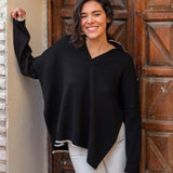 woman showcasing mersea marina polo sweater in black with sand color detail standing on front of wooden door