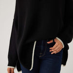 closeup of woman showcasing mersea marina polo sweater in black with sand color detail