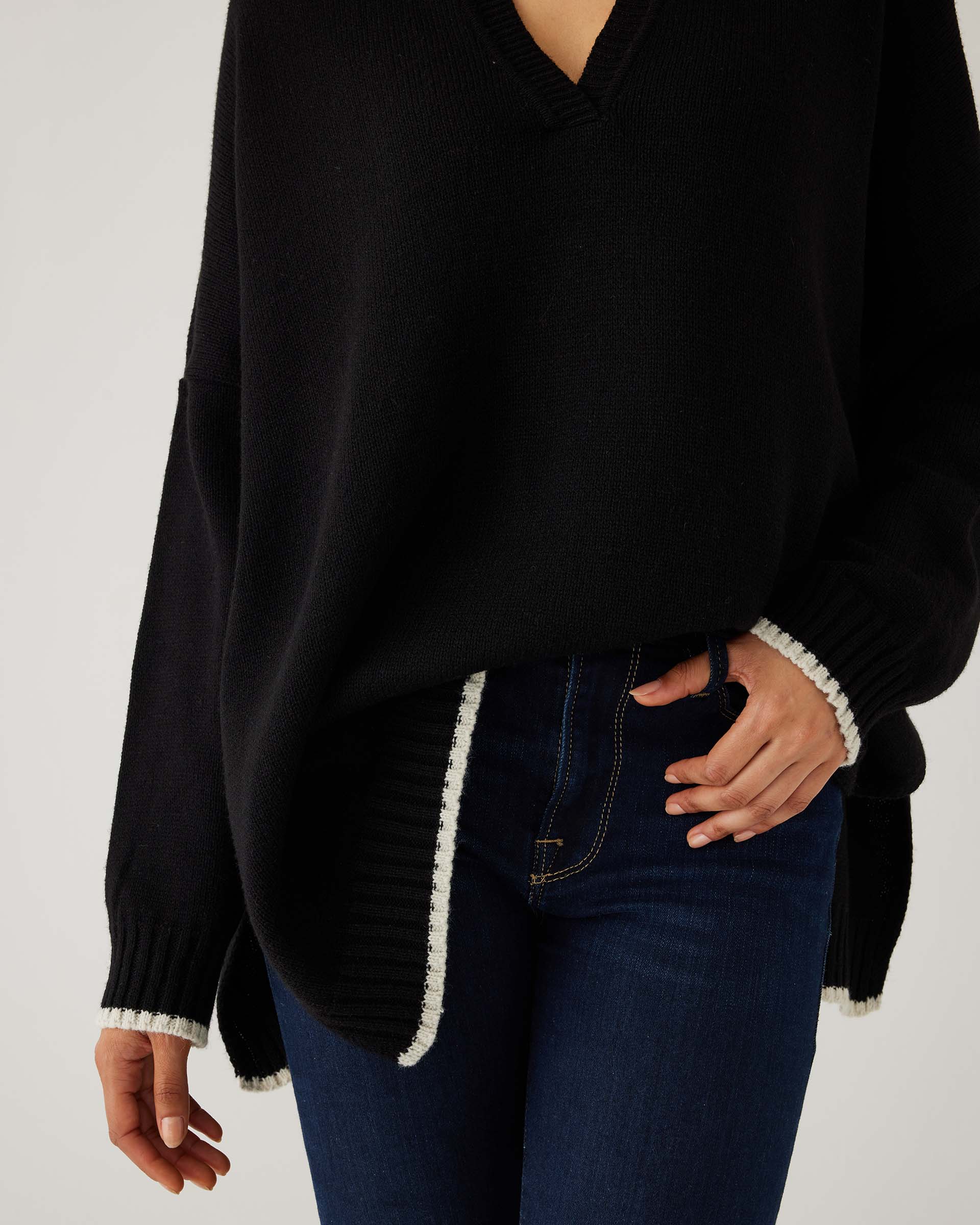 closeup of woman showcasing mersea marina polo sweater in black with sand color detail