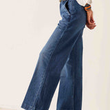 Person wearing blue wide-leg jeans with a plain background