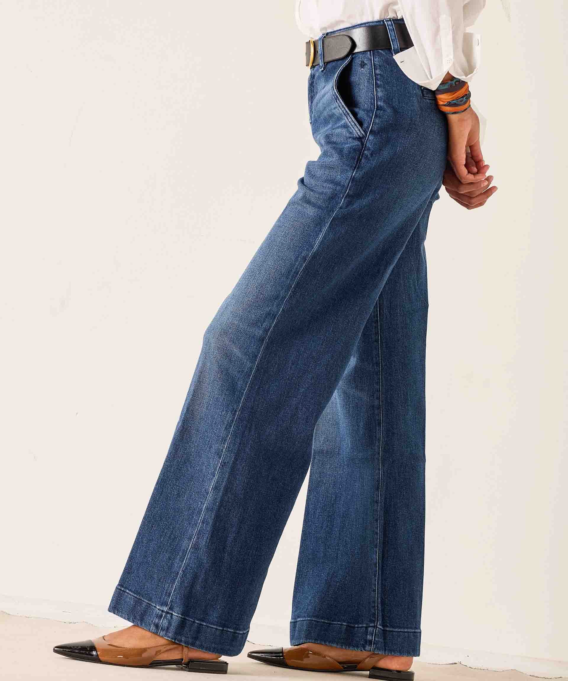 Person wearing blue wide-leg jeans with a plain background