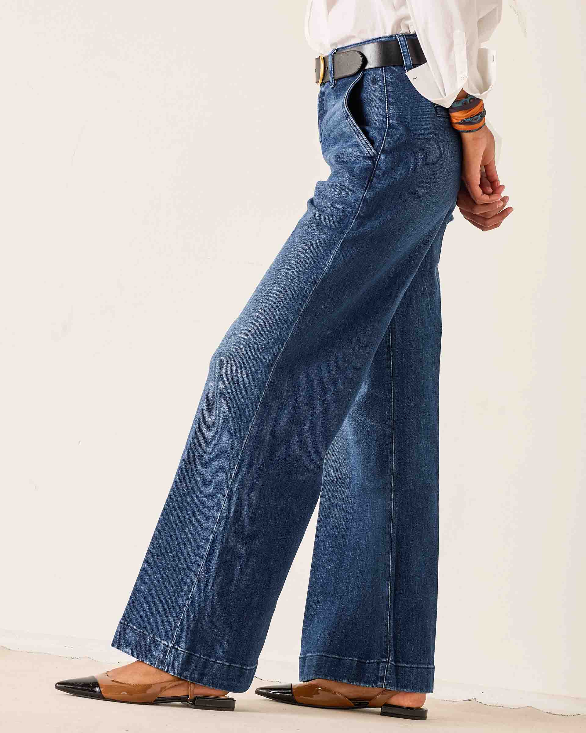 Person wearing blue wide-leg jeans with a plain background