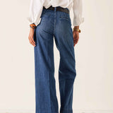 Person wearing blue jeans and a white shirt on a plain background