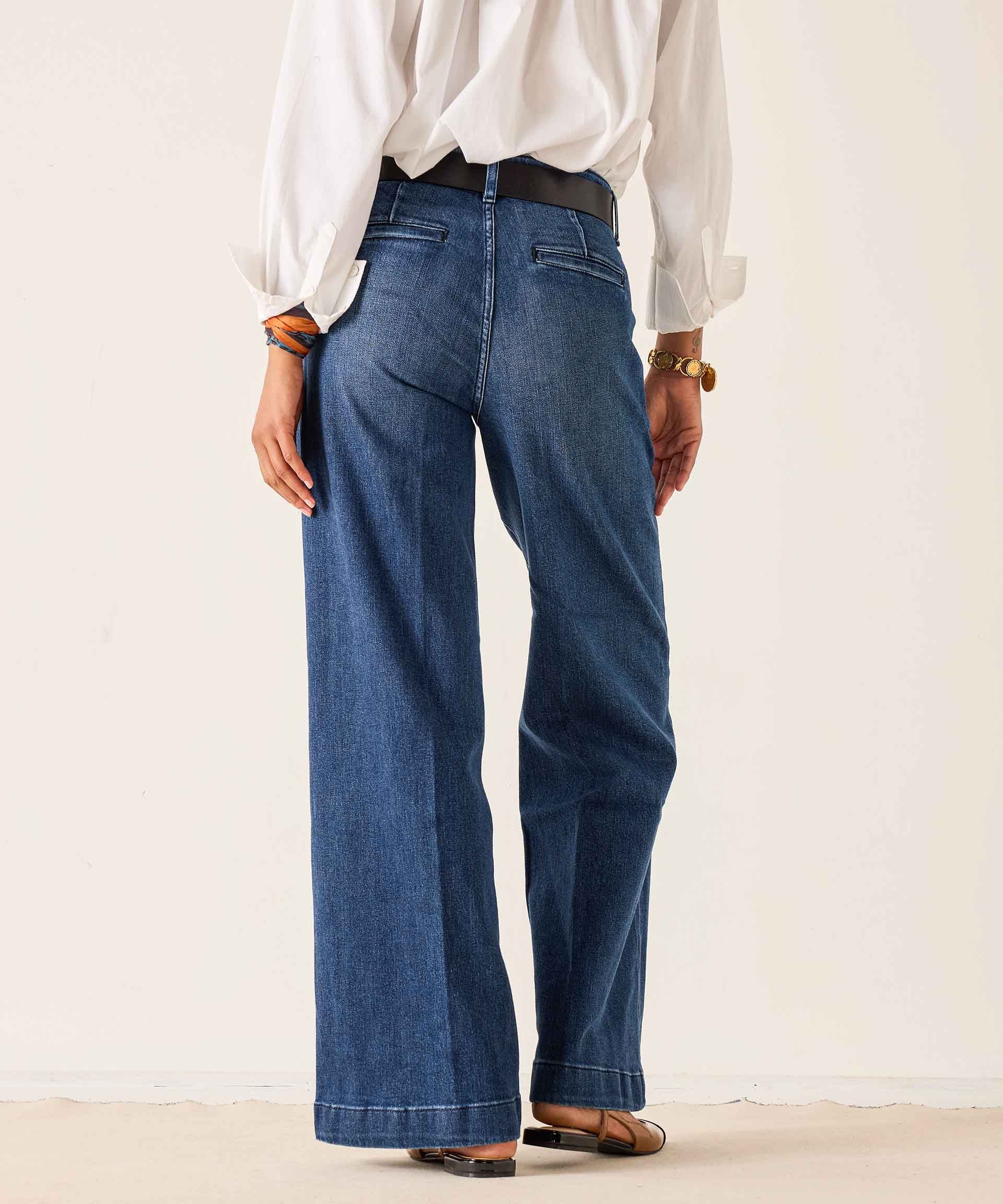 Person wearing blue jeans and a white shirt on a plain background