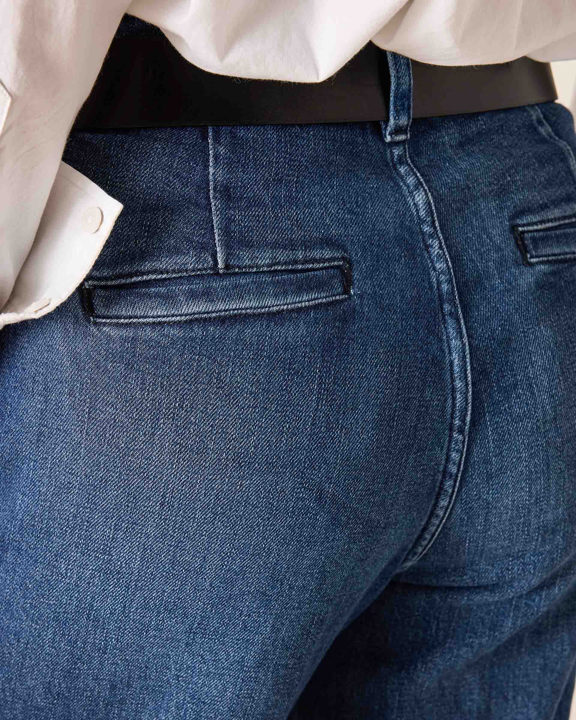 Close-up of blue jeans with a white shirt and black belt.