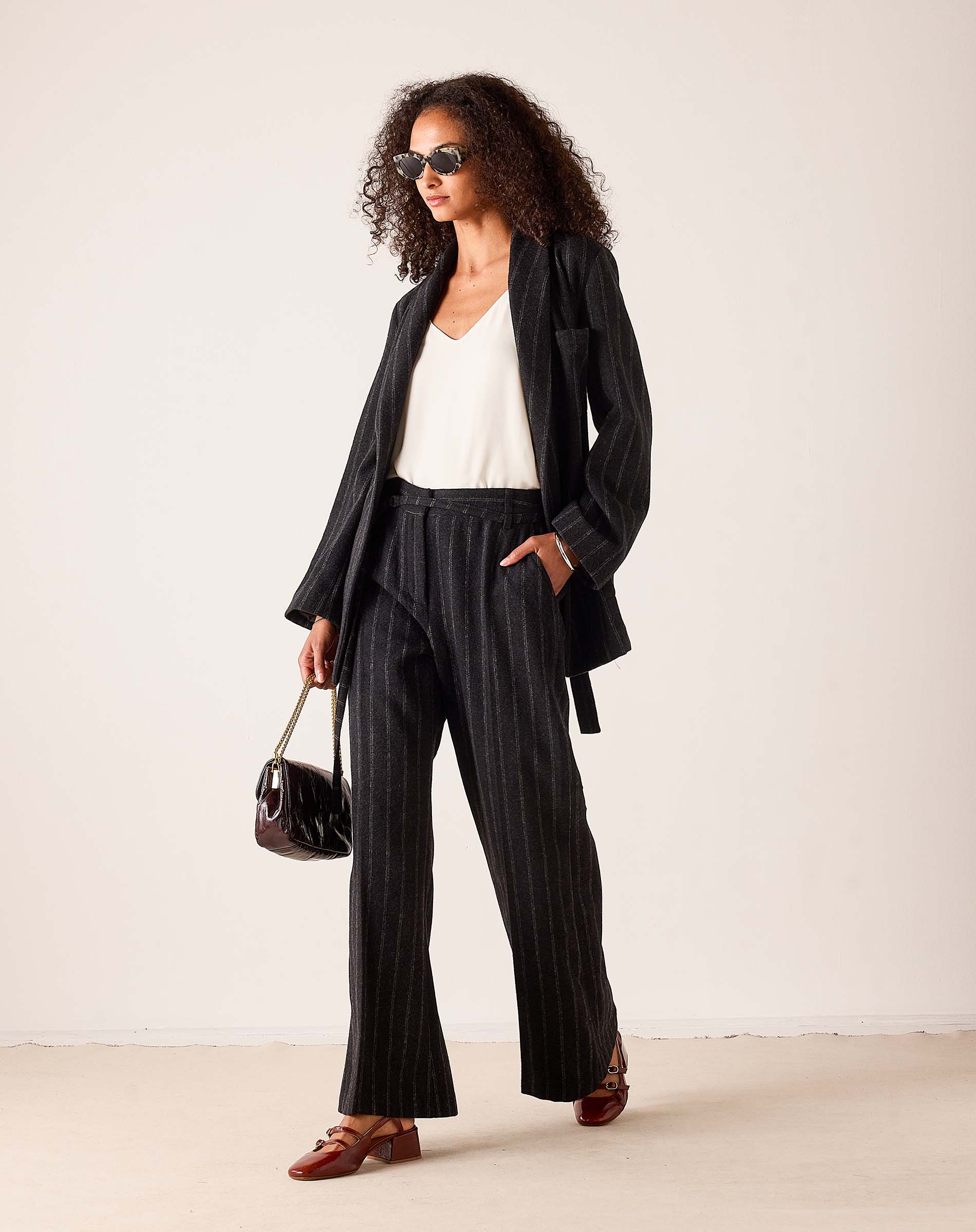 Grey and black vertically striped blazer in a relaxed fit, paired with matching wide-leg trousers and a white top.