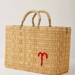 Market straw basket with tan leather handles and Aries symbol embroidered in red