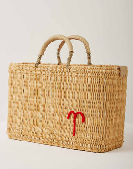 Market straw basket with tan leather handles and Aries symbol embroidered in red