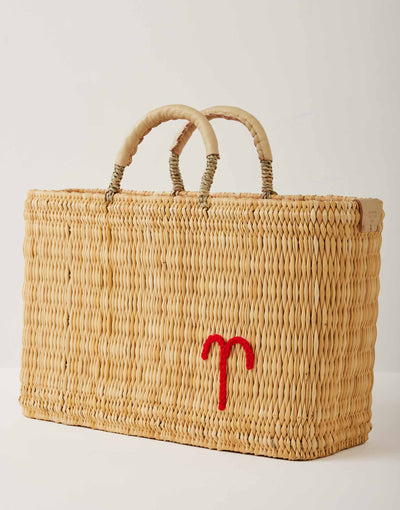 Market straw basket with tan leather handles and Aries symbol embroidered in red