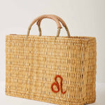 Market straw basket with tan leather handles and Leo symbol embroidered in burnt orange