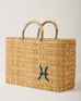 Market straw basket with tan leather handles and Pisces symbol embroidered in teal