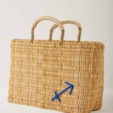 Market straw basket with tan leather handles and Sagittarius symbol embroidered in blue