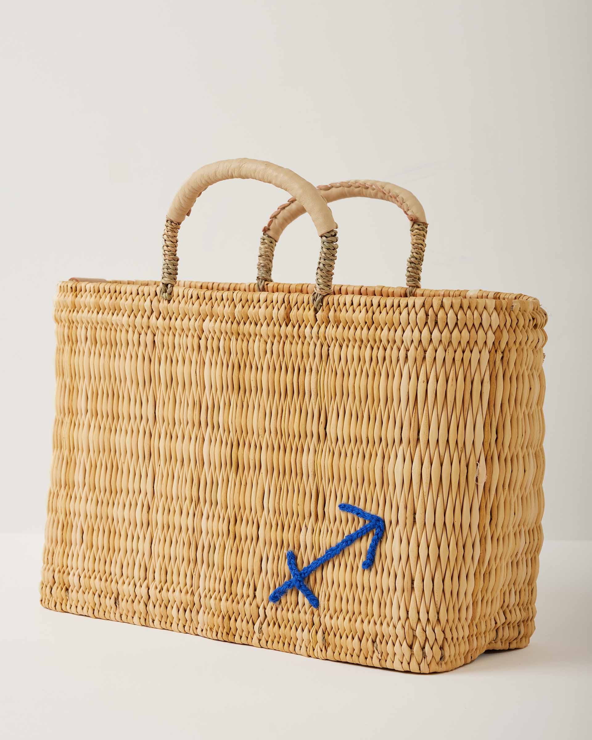 Market straw basket with tan leather handles and Sagittarius symbol embroidered in blue