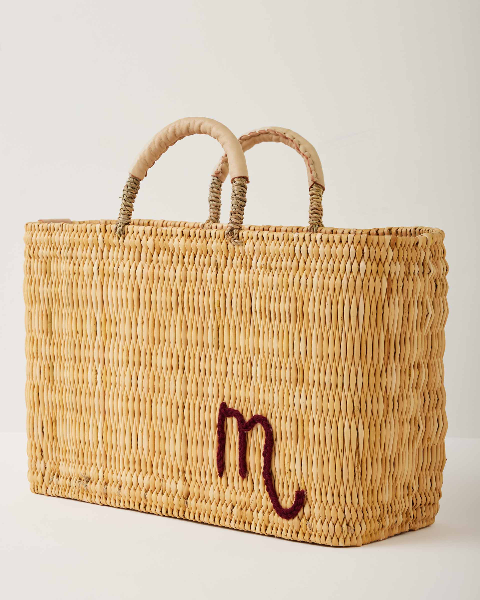 Market straw basket with tan leather handles and Scorpio symbol embroidered in maroon