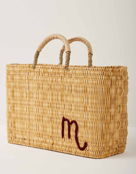 Market straw basket with tan leather handles and Scorpio symbol embroidered in maroon