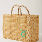 Market straw basket with tan leather handles and Taurus symbol embroidered in foam green